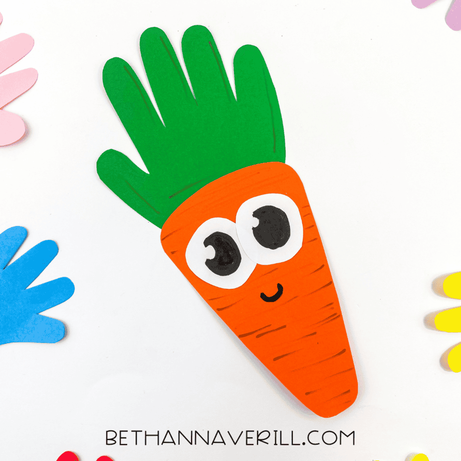 Completed carrot handprint craft on white background with colored paper hands around it