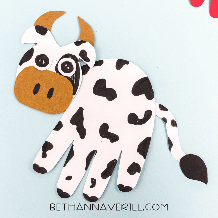 Final staged photo of the cow handprint craft on a light blue background.