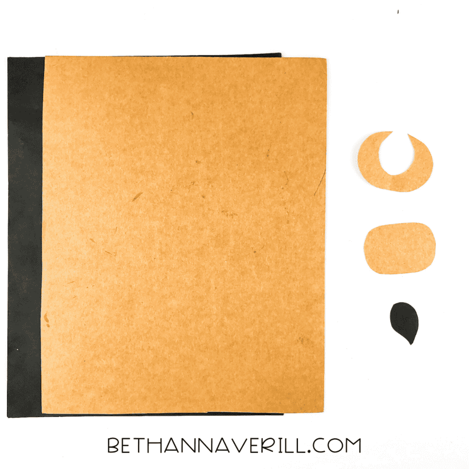 Brown and black construction paper pieces cut for the muzzle, horns, and tail tip.