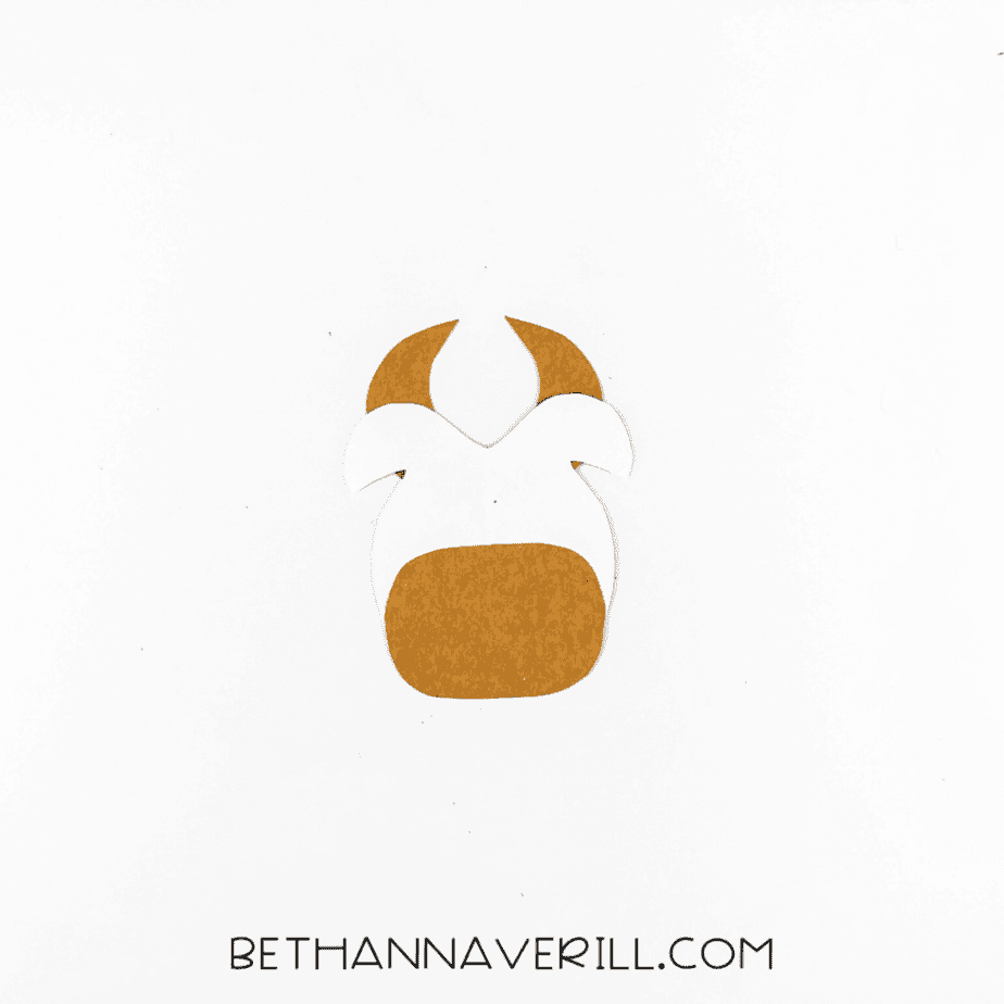 Cow head partially assembled with brown horns and muzzle added to the white head shape.