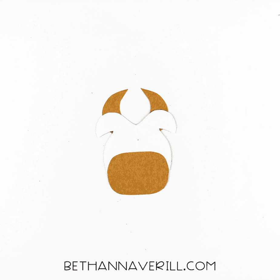 Cow head partially assembled with brown horns and muzzle added to the white head shape.