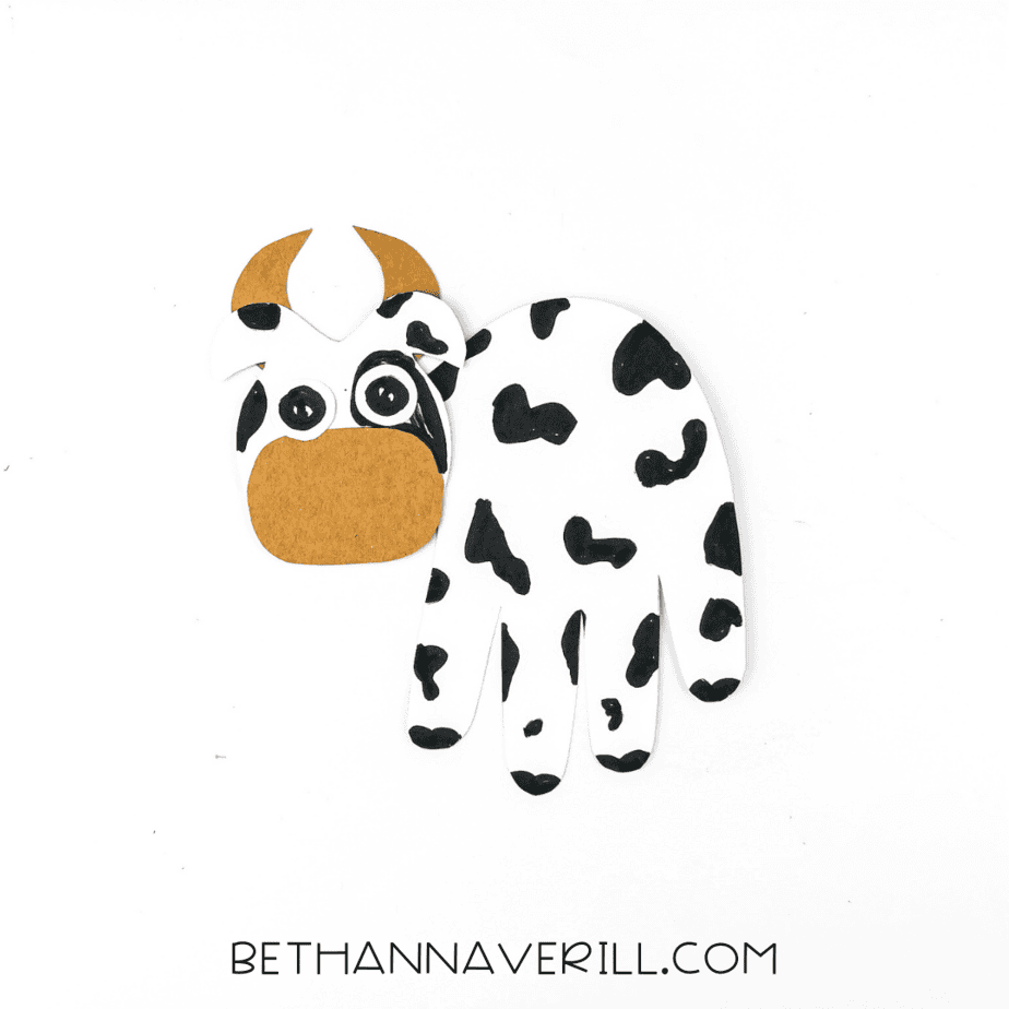 Cow's face and body assembled with the handprint forming the body.