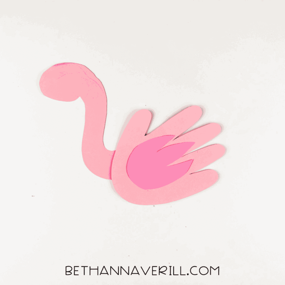 Dark pink wing glued onto flamingo handprint body.