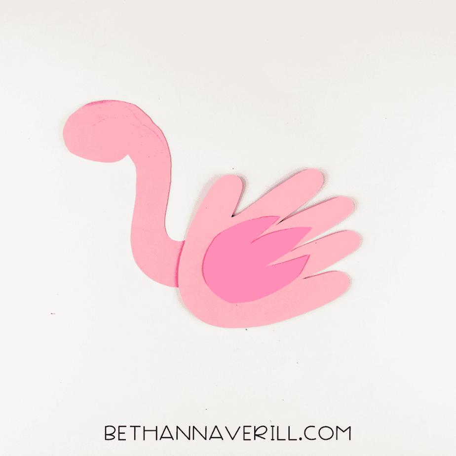 Dark pink wing glued onto flamingo handprint body.