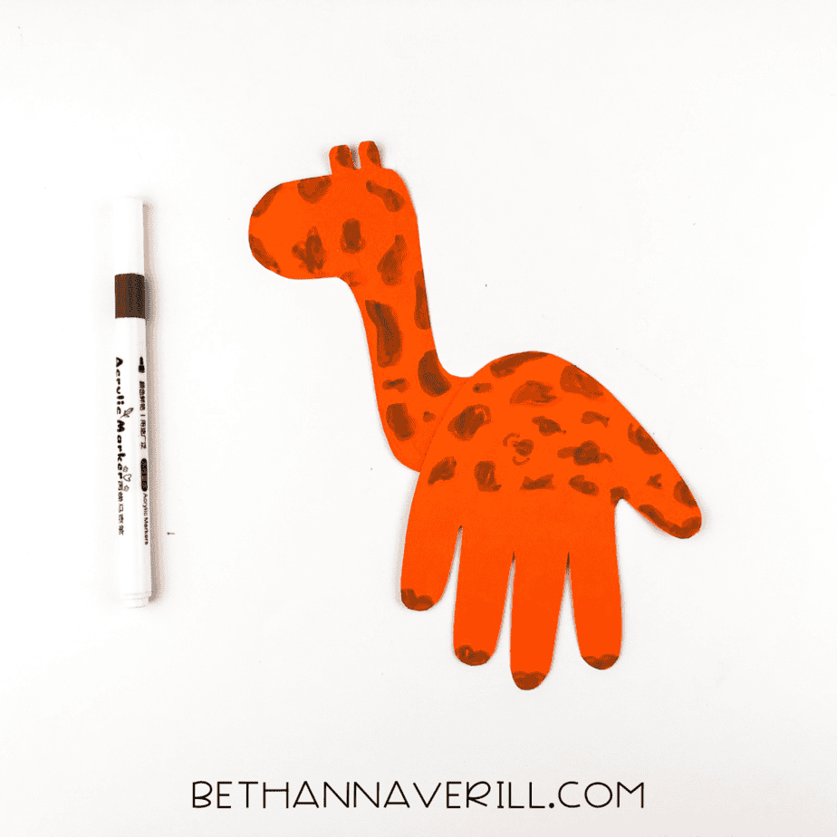 Brown spots drawn on giraffe handprint body with brown marker shown.