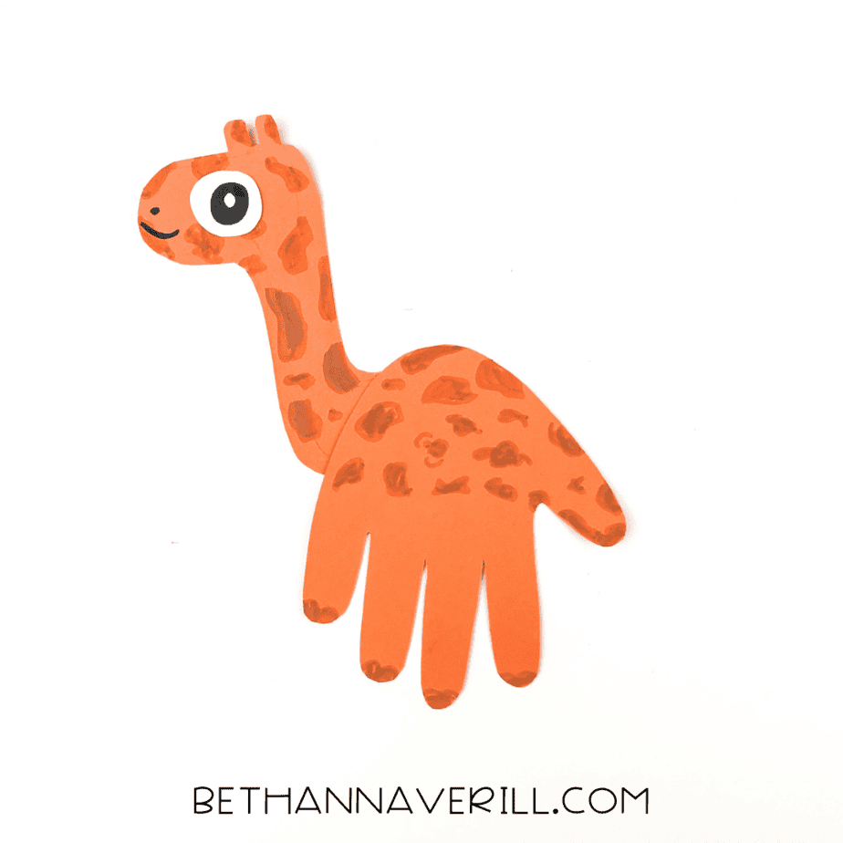 Completed orange giraffe handprint craft with smile and spots.