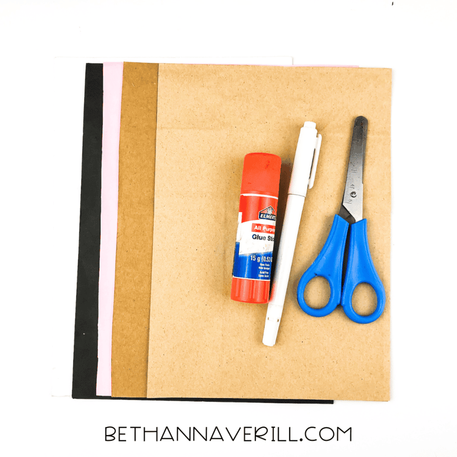 Supplies needed for monkey handprint craft including paper, glue stick, scissors, and pen.