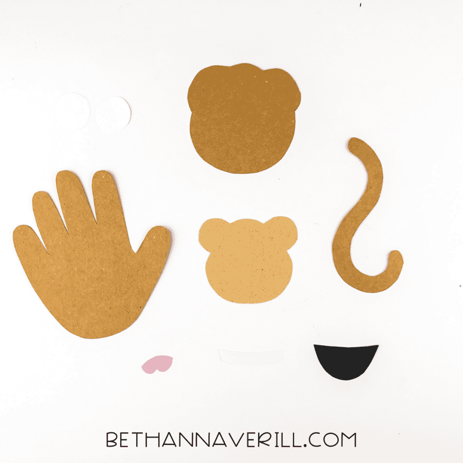 All monkey craft pieces cut from colored paper including handprint, face, tail, and mouth parts.
