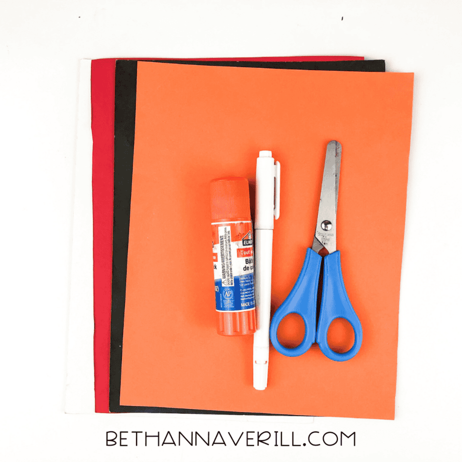 Materials for monster handprint craft including glue, scissors, paper, and pen.