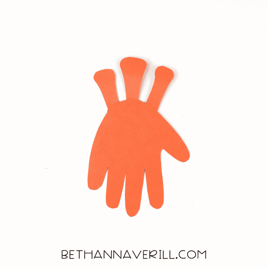 Orange handprint with three rounded eye stalk pieces glued behind it.