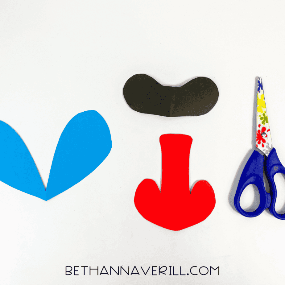 Cut construction paper shapes for the baboon's face: blue cheek patches, red nose, and black eye mask.