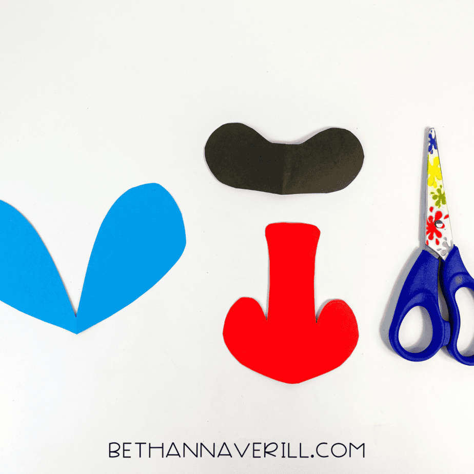 Cut construction paper shapes for the baboon's face: blue cheek patches, red nose, and black eye mask.