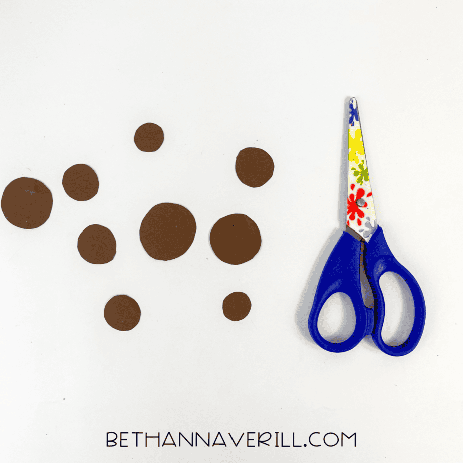 Scissors next to cut-out paper pieces for cheetah’s spots.