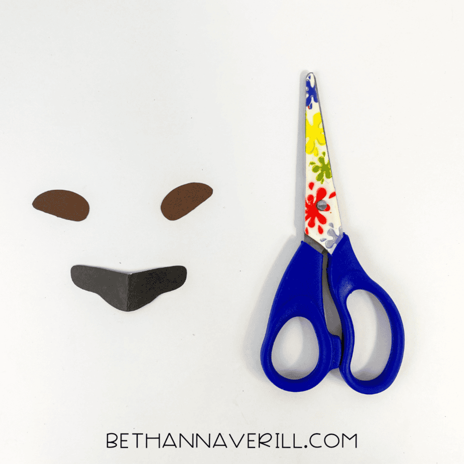 Scissors next to cut-out paper pieces for cheetah’s nose and eyebrows