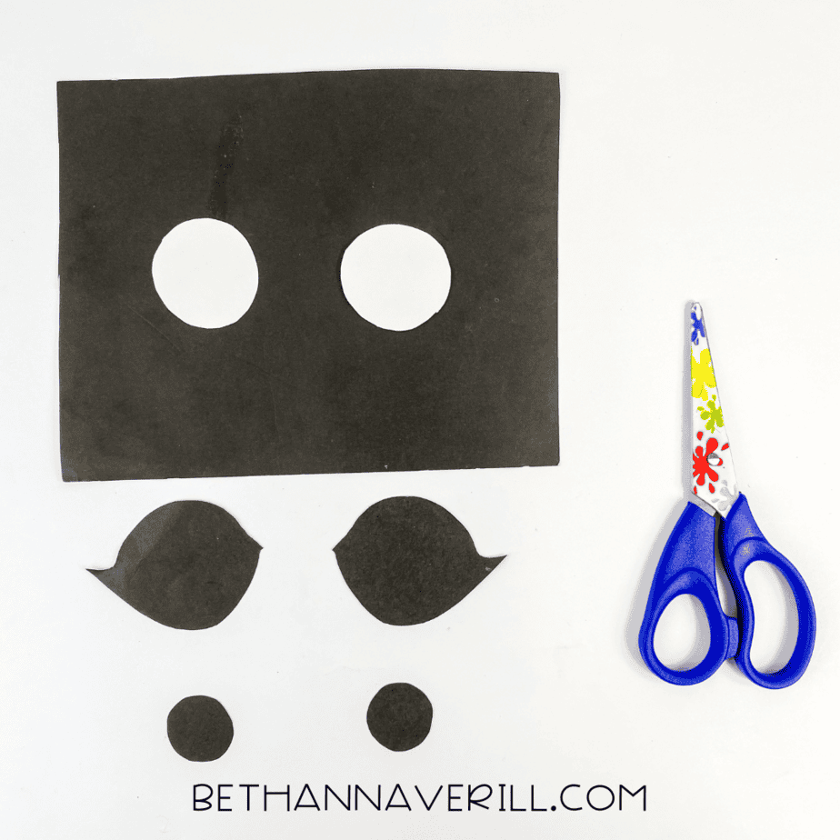 Scissors next to cut-out paper pieces for cheetah’s eyes