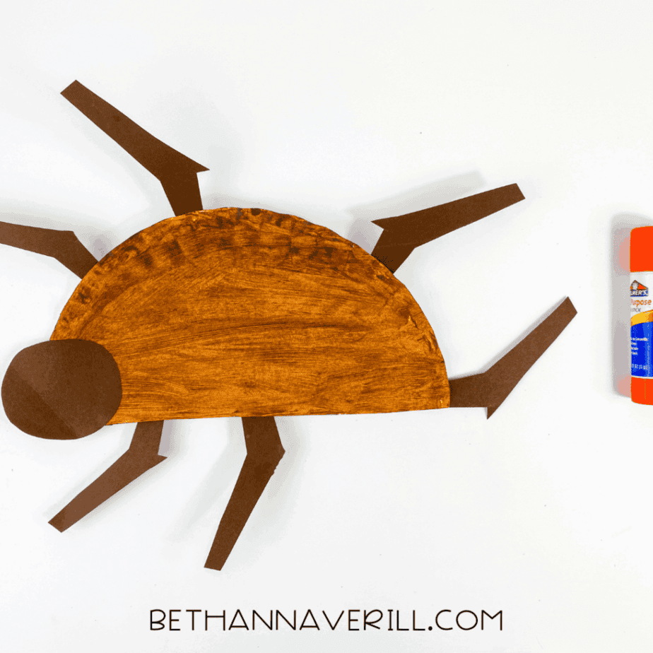 Brown paper plate half with legs and head glued in place.