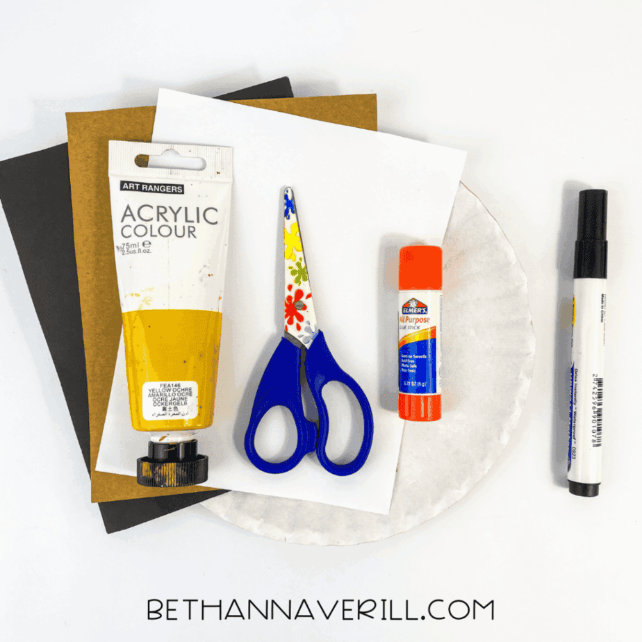 Materials needed for the paper plate hyena craft laid out on a white background