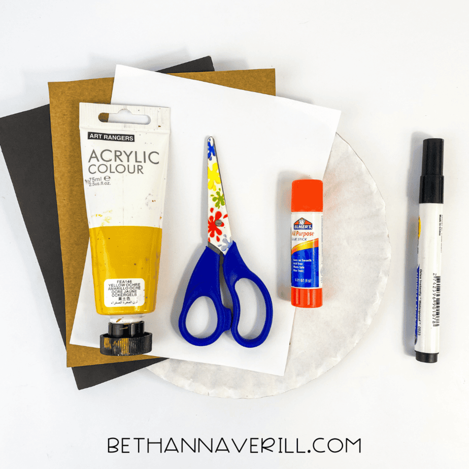 Materials needed for the paper plate hyena craft laid out on a white background