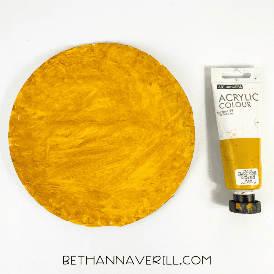 Paper plate painted fully yellow with yellow acrylic paint beside it