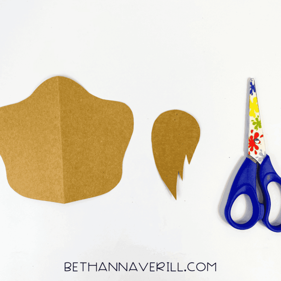 Brown paper pieces cut into a snout and hair tuft shape, scissors nearby
