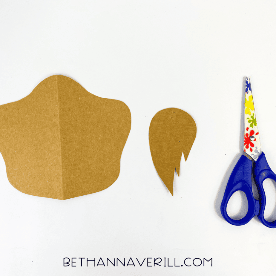 Brown paper pieces cut into a snout and hair tuft shape, scissors nearby