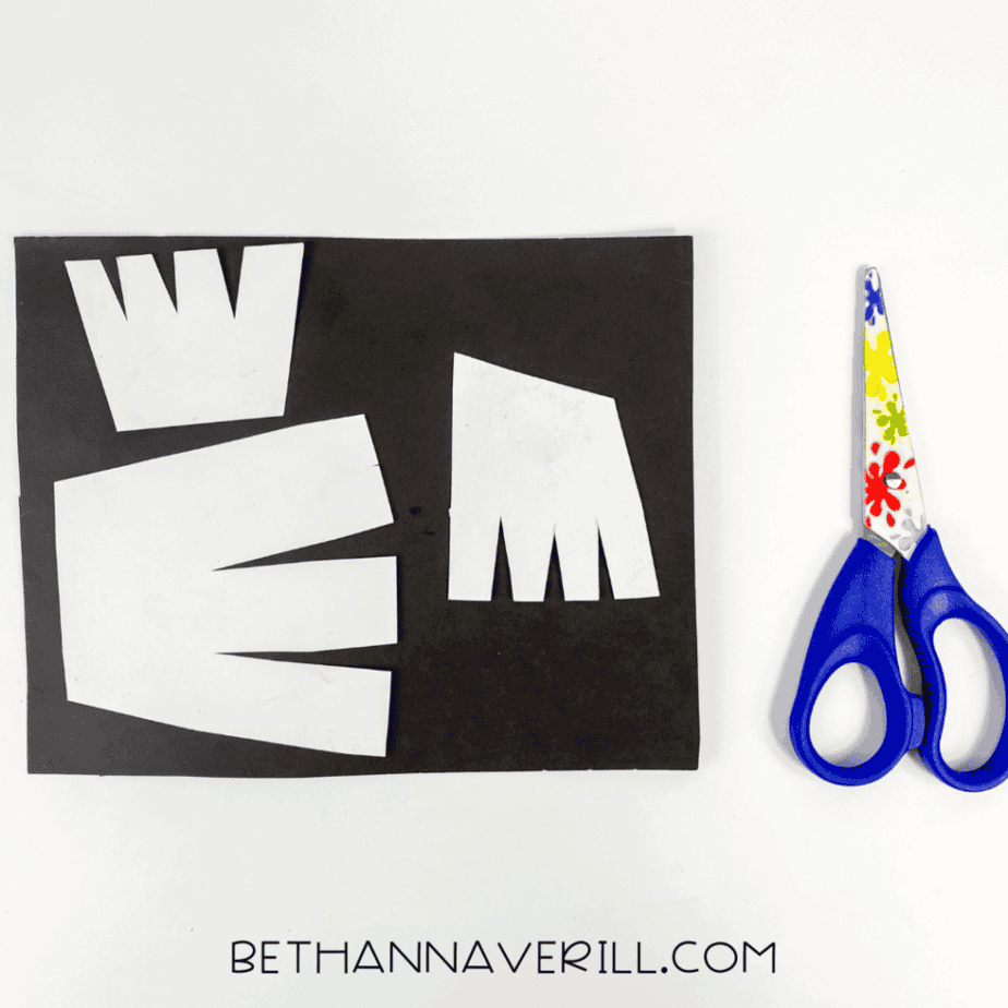 White feather shapes cut out on top of black construction paper.