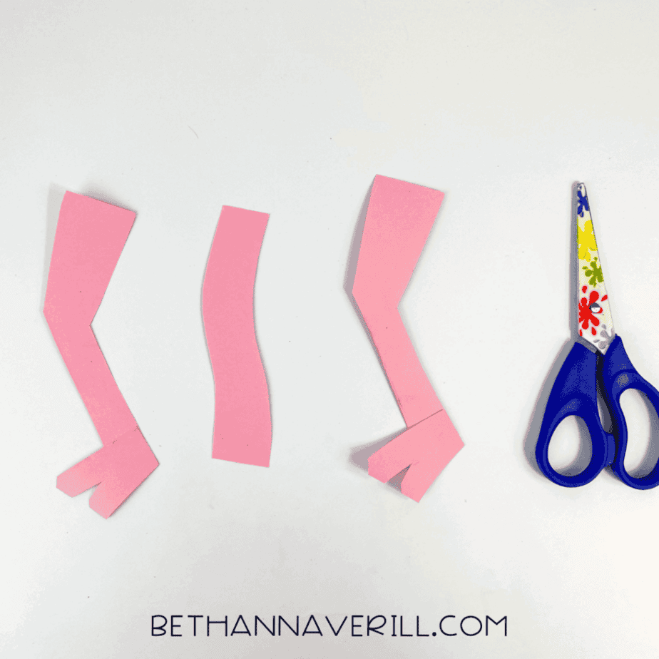 Three pink ostrich leg and neck pieces cut out and laid flat.