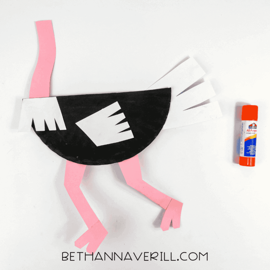 Paper plate body with pink legs and neck glued in place.