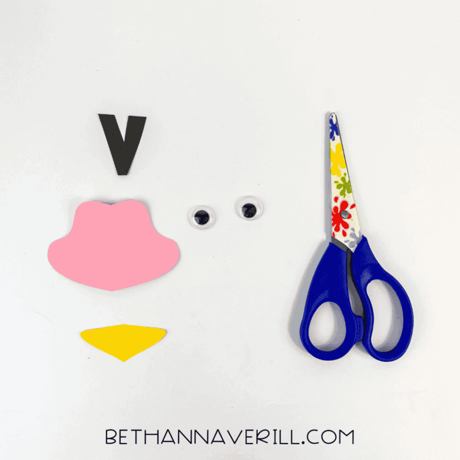 Construction paper pieces for the ostrich head laid out with scissors and googly eyes.