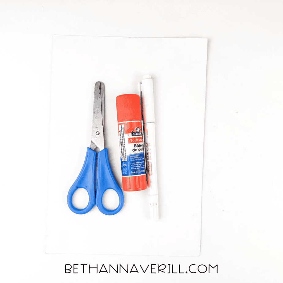 Supplies for polar bear craft including white paper, scissors, glue stick, and marker