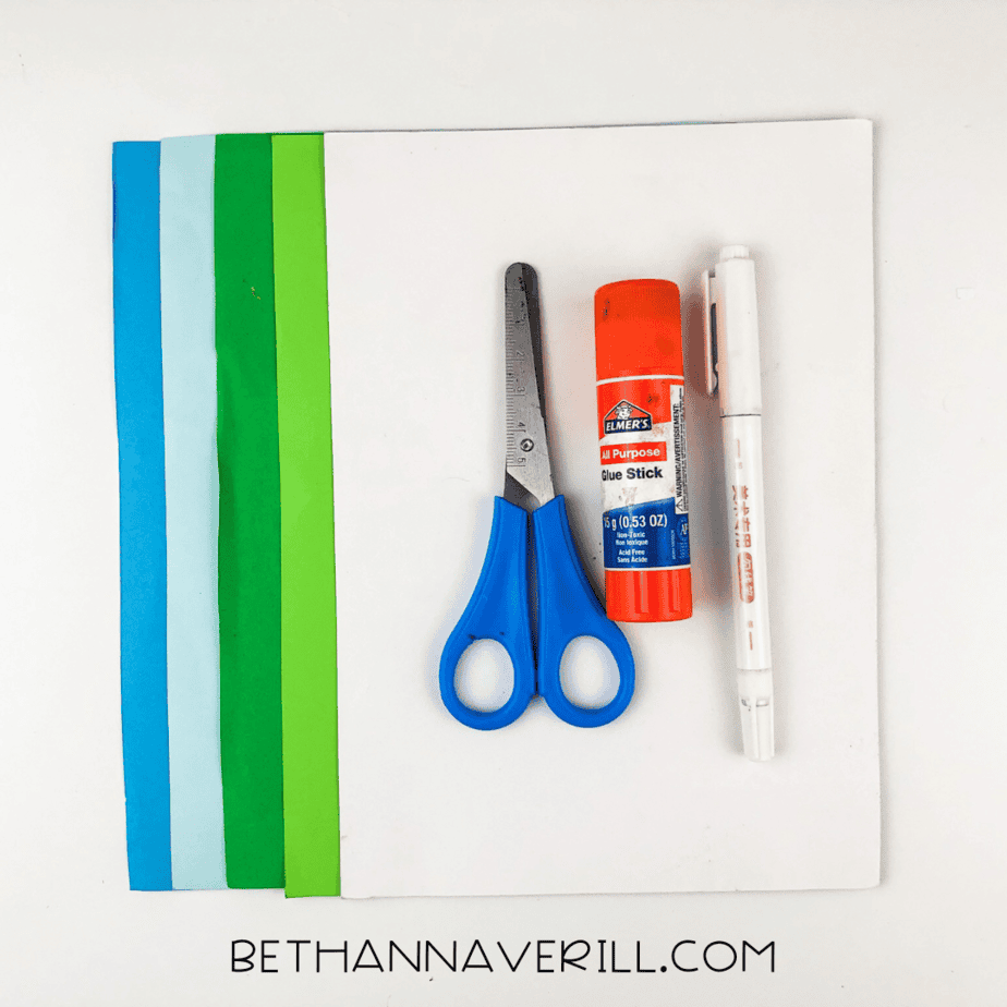 Craft supplies including colored paper, glue stick, scissors, and a marker.