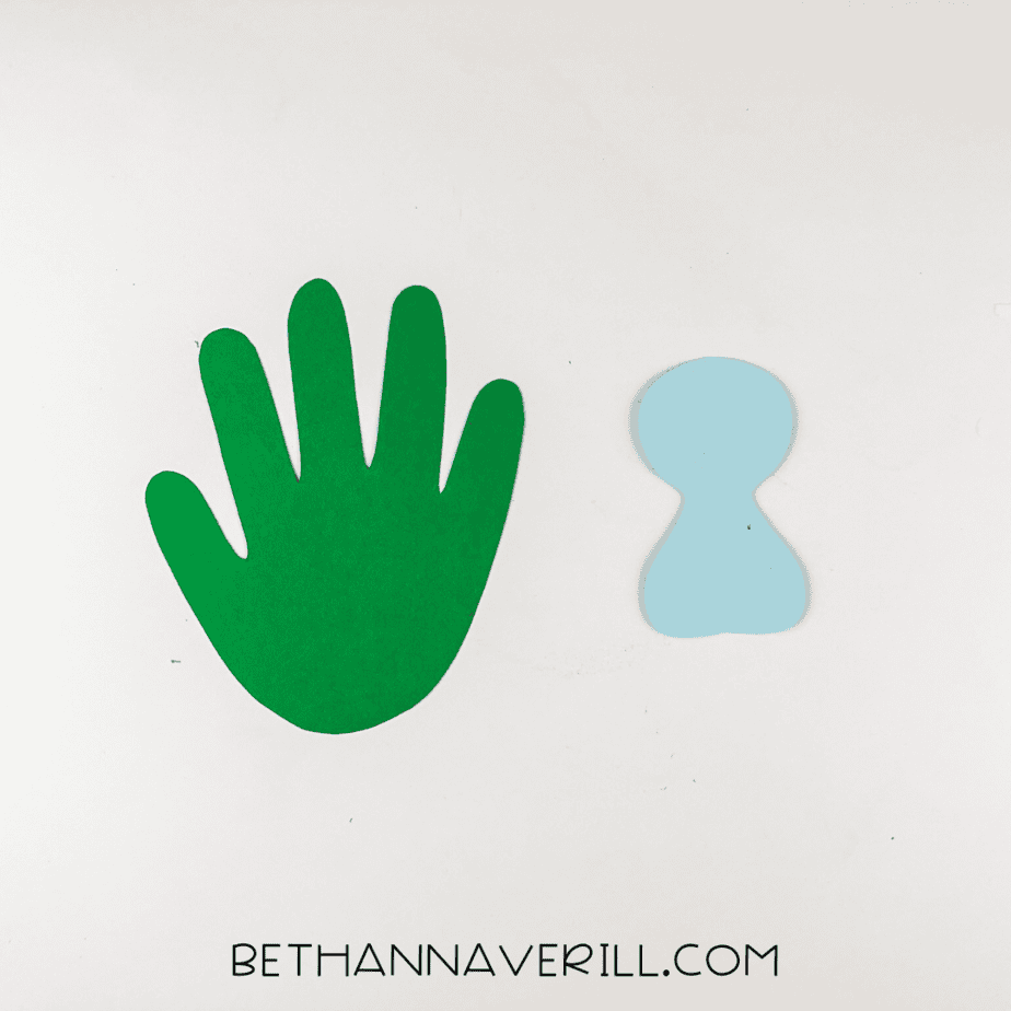 Green paper handprint and light blue peacock body cutouts.