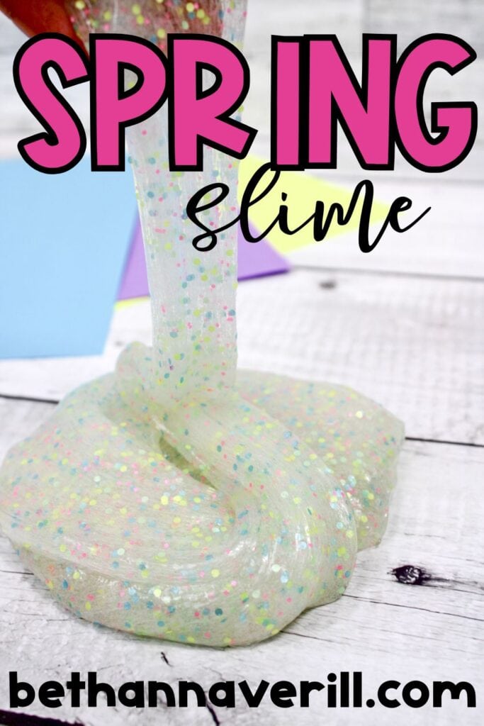 Clear slime filled with tiny pastel confetti is being stretched upward over a white wooden background, with colorful paper squares in the background. “Spring Slime” is written in bright pink and black letters, with “bethannaverill.com” below.