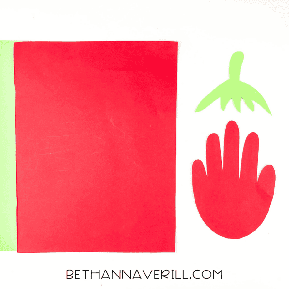 Cut pieces of red handprint and green leaf top next to red and green paper