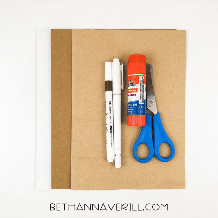 Craft supplies laid out: brown construction paper, markers, glue stick, scissors.