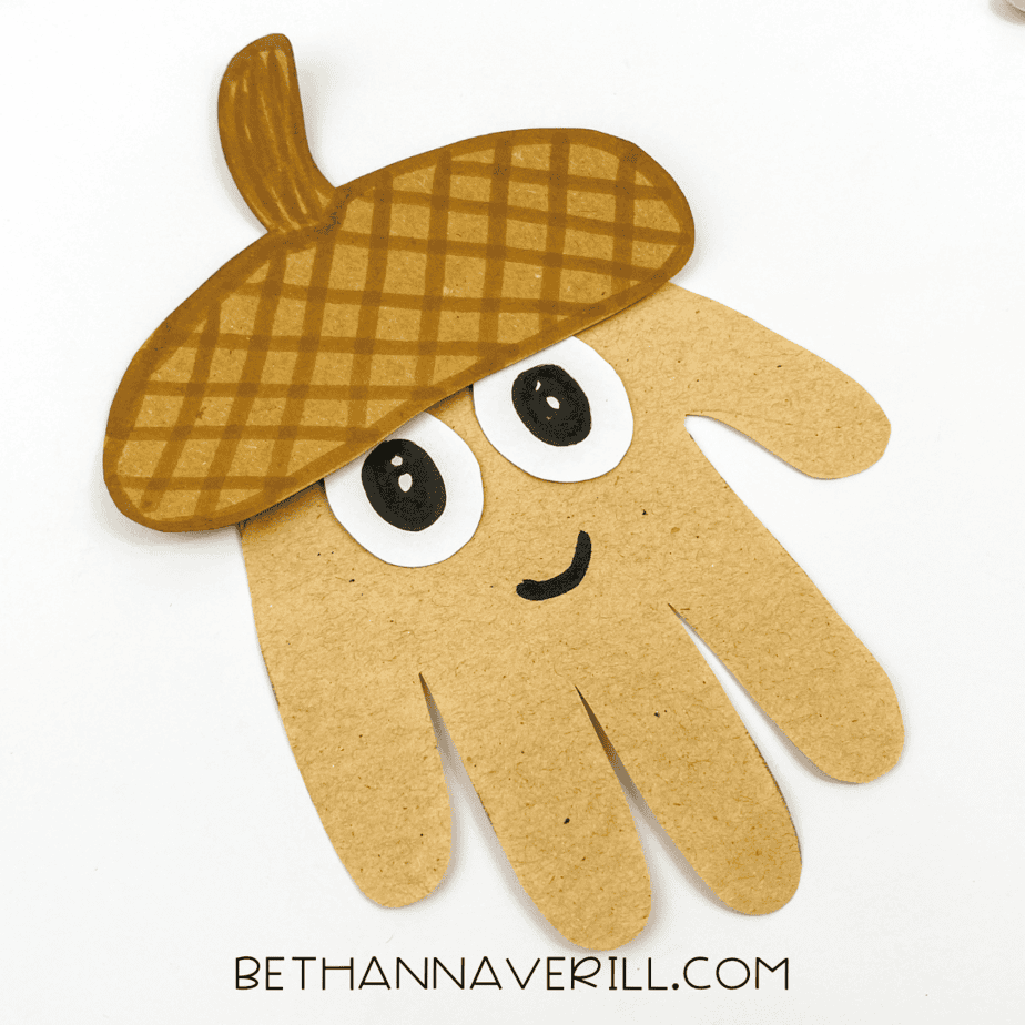 Finished acorn handprint craft with a smiling face.