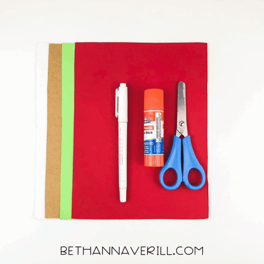 Craft supplies laid out: red, green, brown, and white paper, glue stick, scissors, and markers.