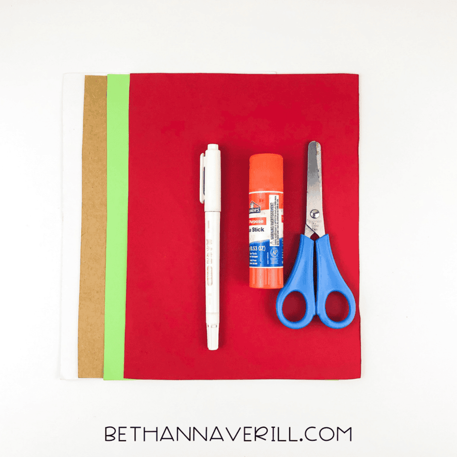 Craft supplies laid out: red, green, brown, and white paper, glue stick, scissors, and markers.