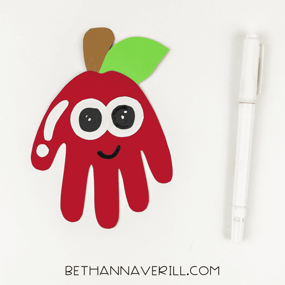 face drawn on the apple handprint with a black marker.