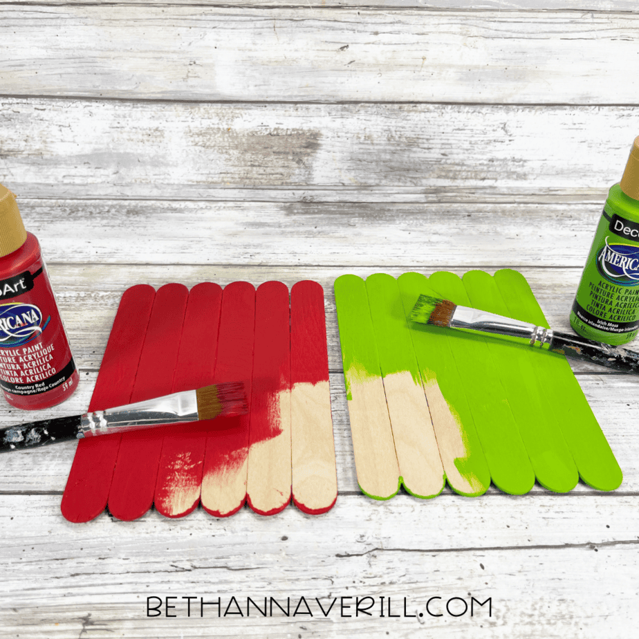 Popsicle sticks painted bright red and green with paintbrushes.