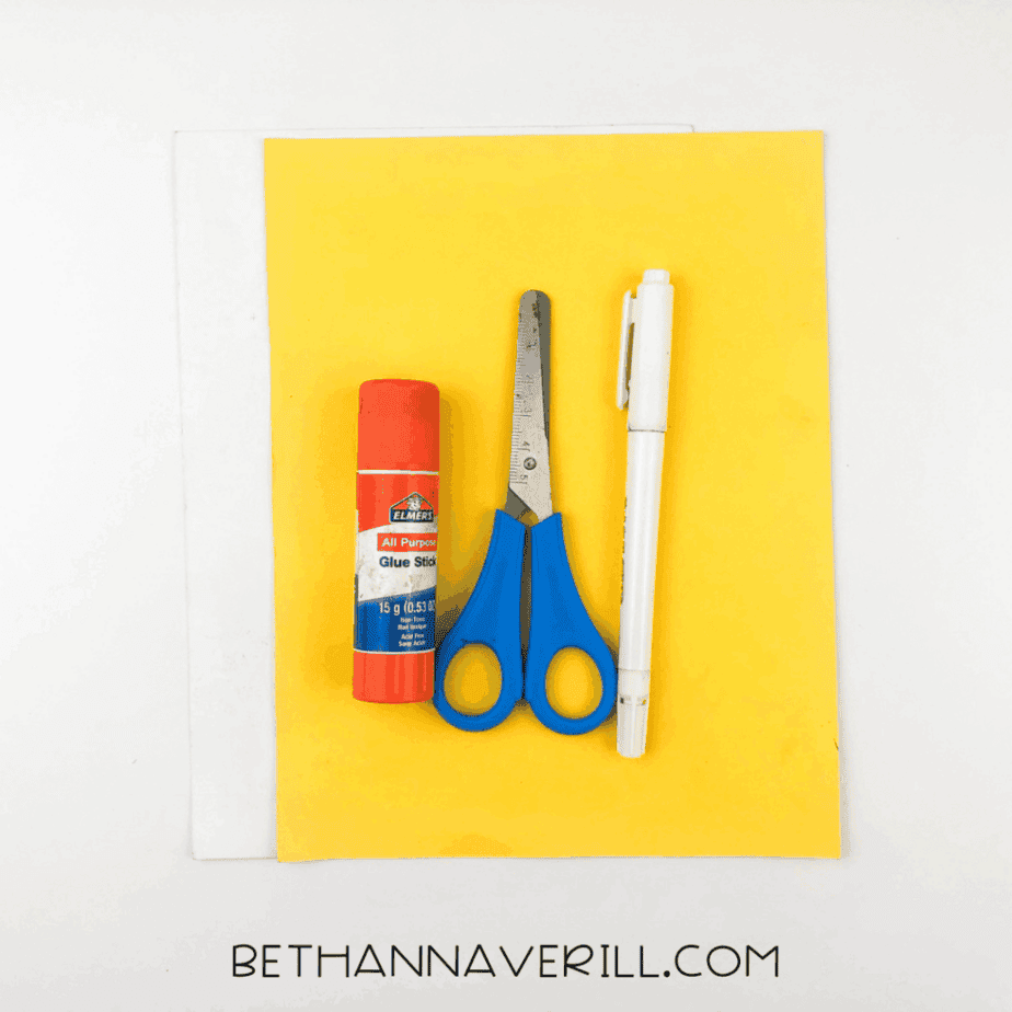 Supplies laid out: yellow and white paper, glue stick, scissors, and markers.