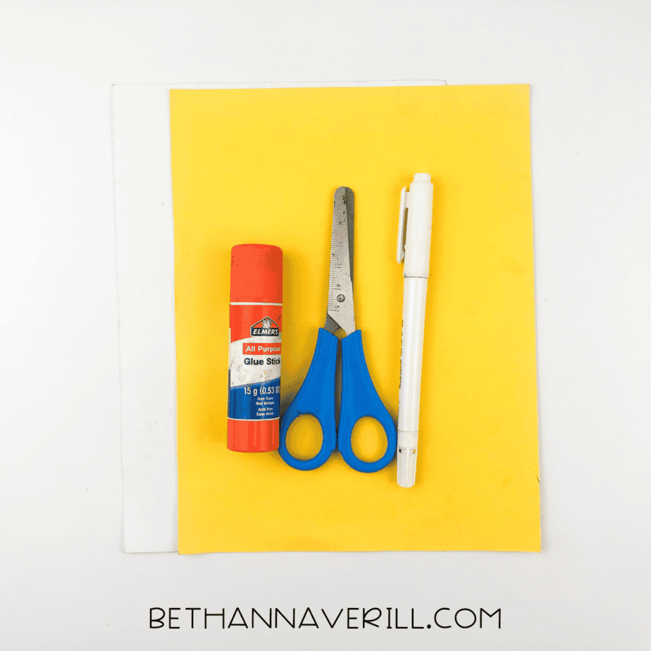 Supplies laid out: yellow and white paper, glue stick, scissors, and markers.