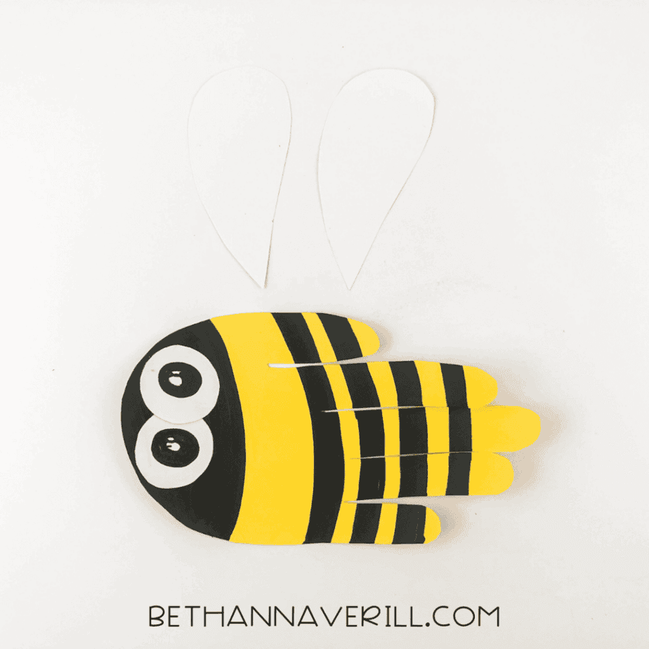 Bee craft laid out with two unglued wings nearby.