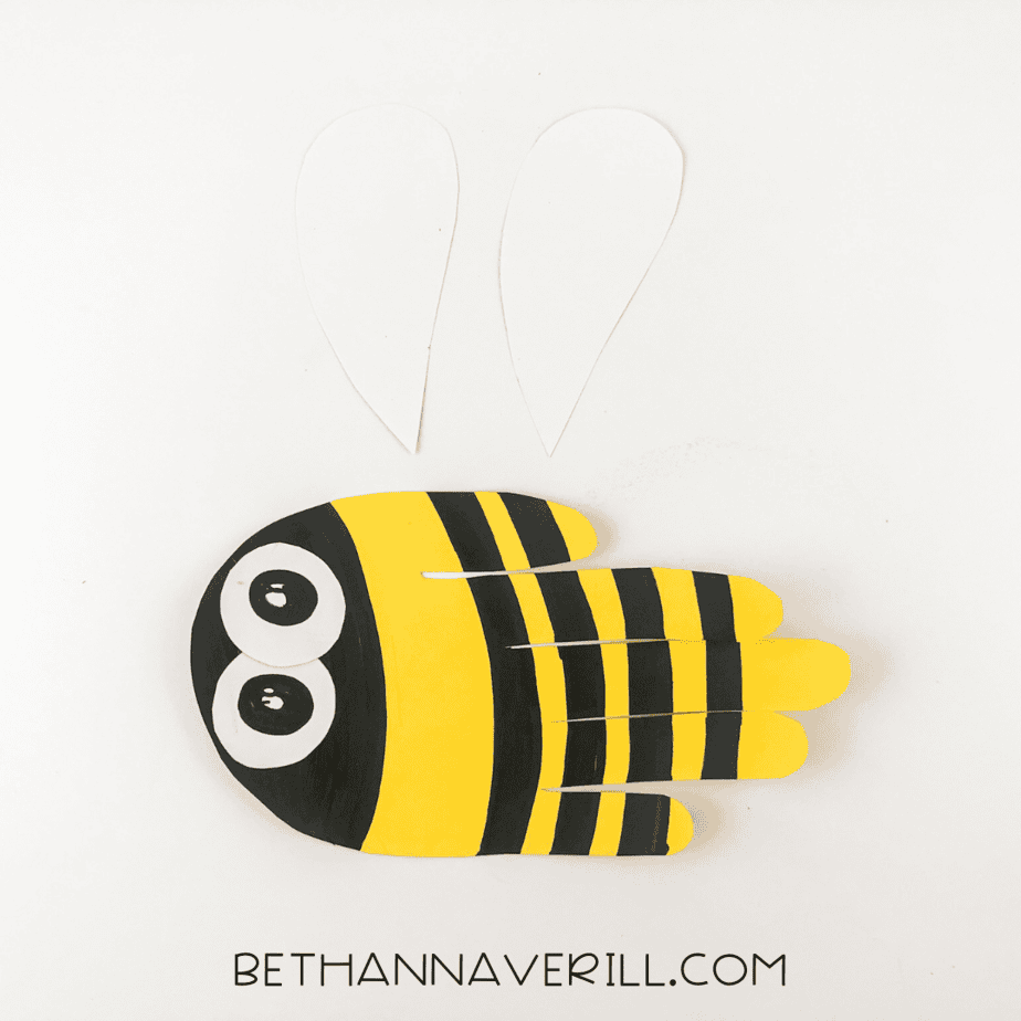 Bee craft laid out with two unglued wings nearby.
