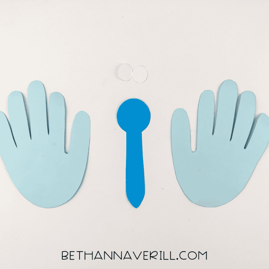 Cut pieces for the butterfly: two light blue handprints, a blue body, and white eyes.