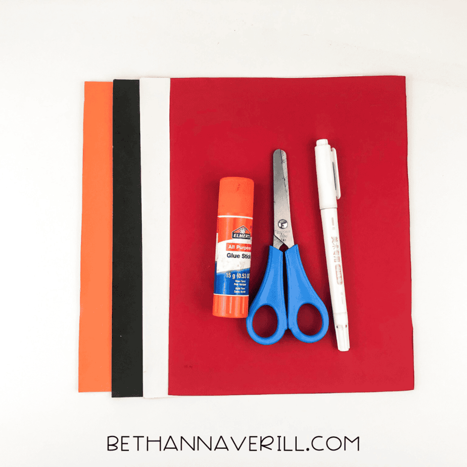 Craft materials including construction paper, glue stick, scissors, and black marker