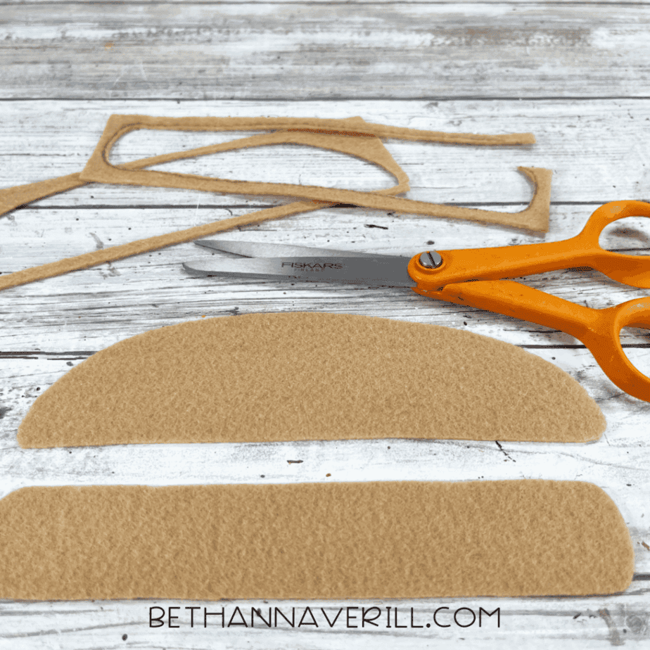Cut tan felt burger bun pieces with scissors.
