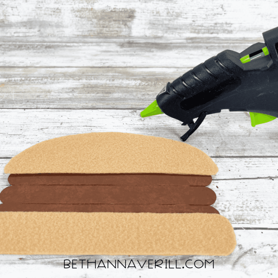 Tan felt burger bun glued to top and bottom of popsicle stick patty.