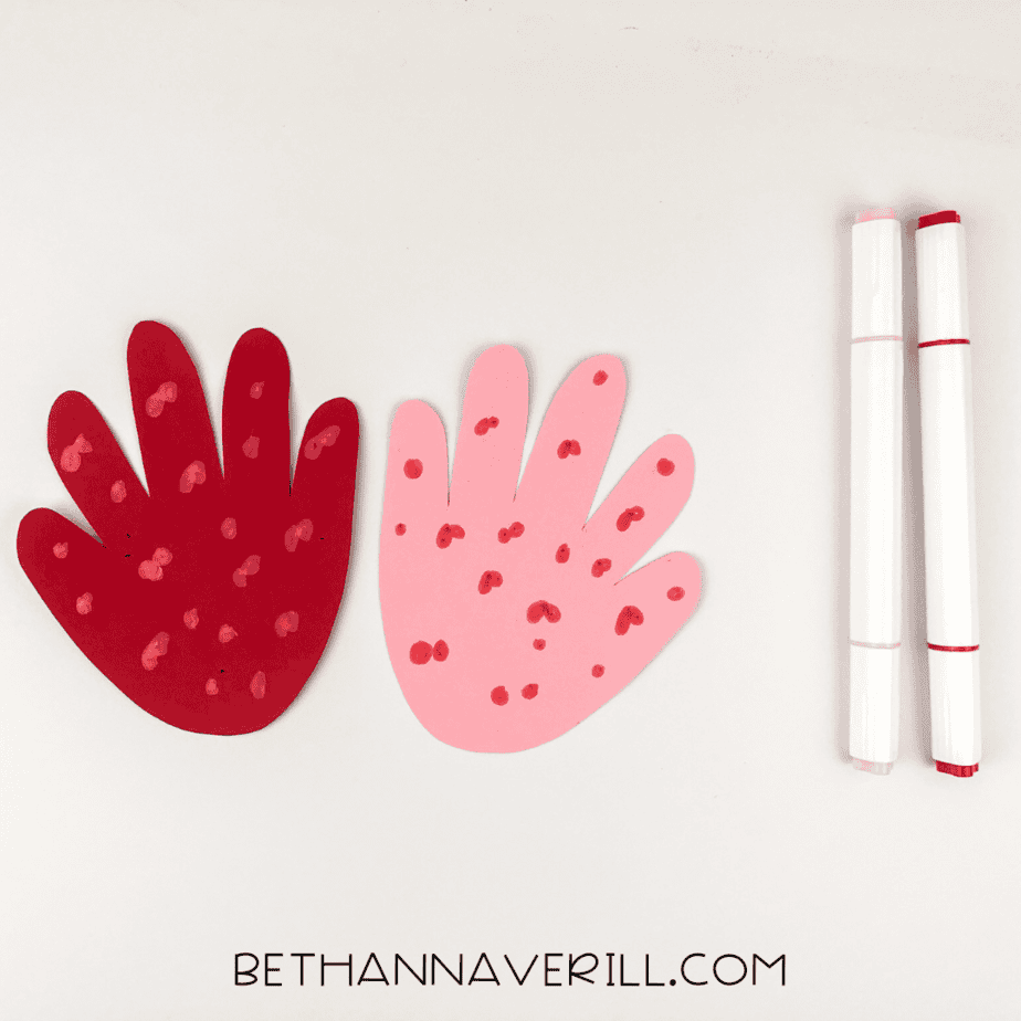 Pink and red handprints decorated with blossom dots using markers