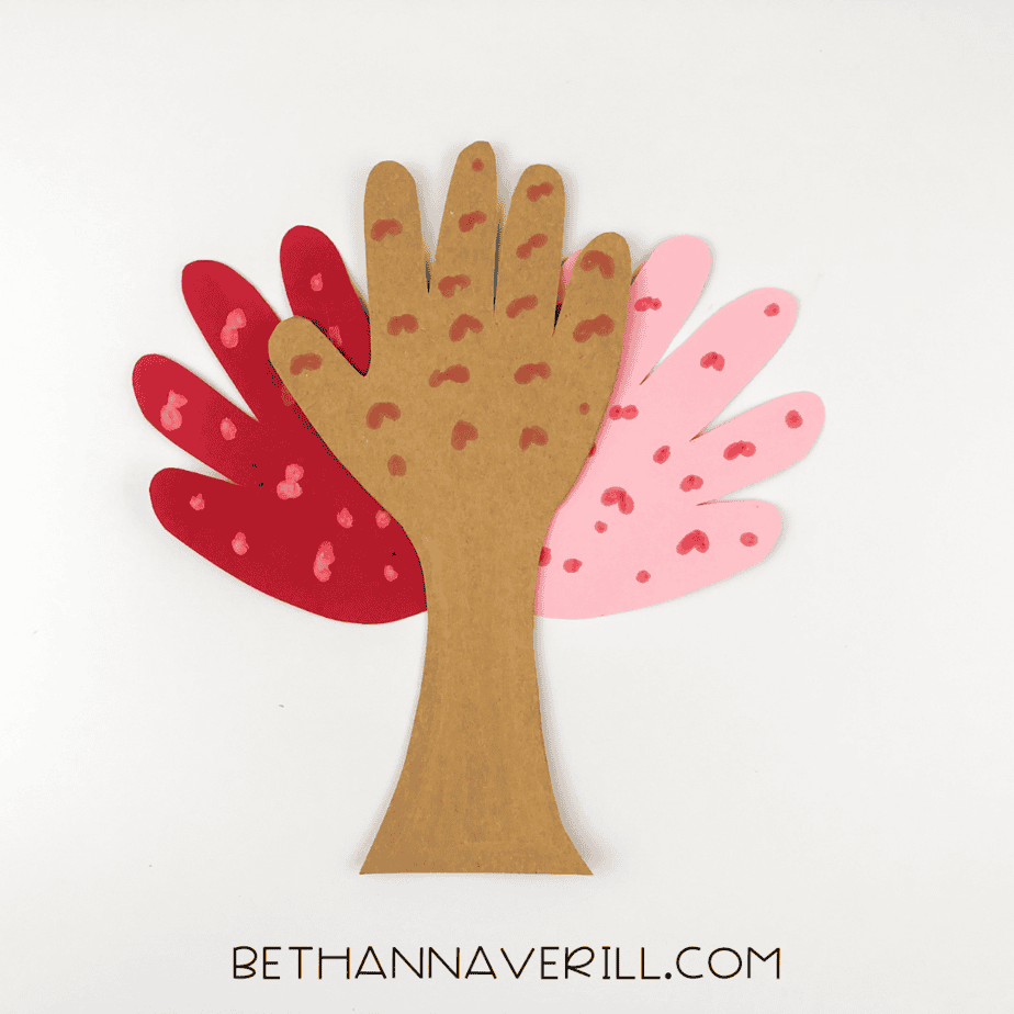 Assembled cherry blossom tree with trunk layered over pink and red handprints